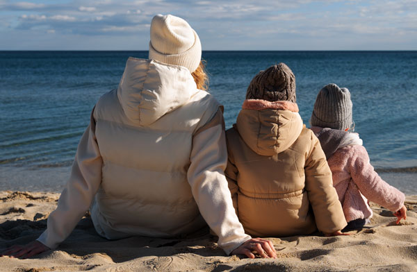 Family sitting on the beach dressed in winter clothes
